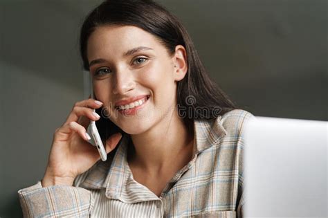 Young Brunette Woman Talking On Cellphone While Working With Laptop
