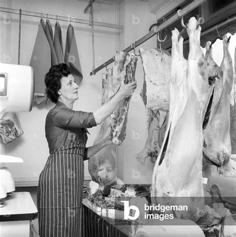 A Female Butcher Seen Here At Work In Her Shop Hanging Up Joints On