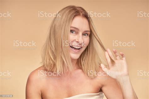 Portrait Of A Happy And Beautiful Mature Blonde Woman Touching Her Hair