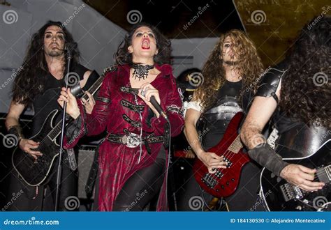 Female Vocalist Dressed In Red Singing Between Two Long Haired Rockers