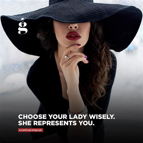 A Woman Wearing A Large Black Hat And Holding Her Hand To Her Face With