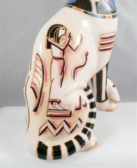 A Ceramic Figurine Of An Egyptian God On A White Surface With Black And