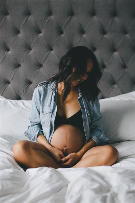 A Pregnant Woman Sitting On A Bed With Her Belly Tucked Under Her