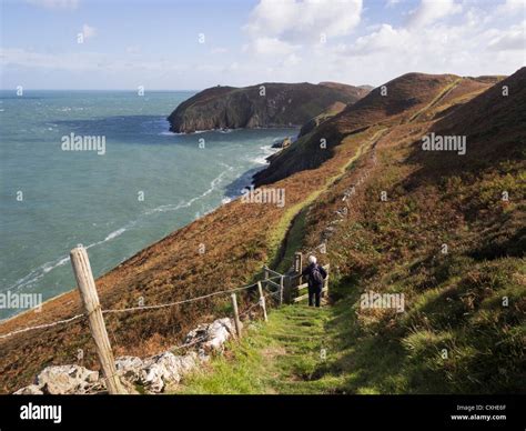 Walker Walking Down Stepped Section Of Isle Of Anglesey Coastal Path