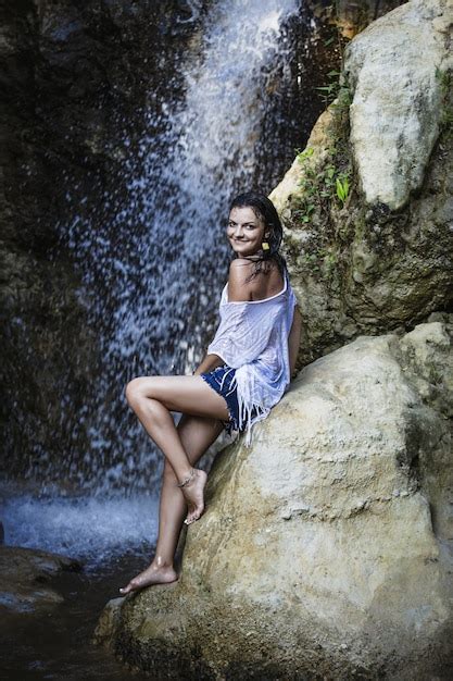 linda modelo feminina feliz e sexy no fundo de uma cachoeira nos trópicos foto premium