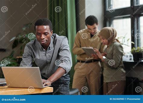 Young African American Businessman Bending Over Desk With Laptop And