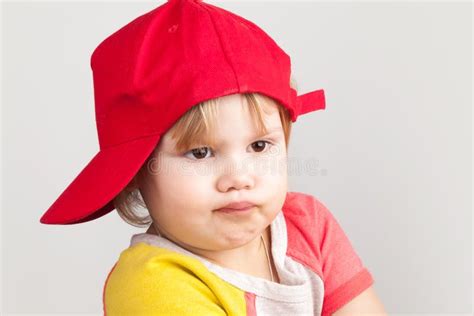 Studio Portrait Of Funny Confused Girl In Red Baseball Cap Stock Image