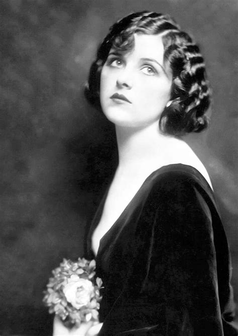 An Old Black And White Photo Of A Woman In A Velvet Dress Holding A Flower