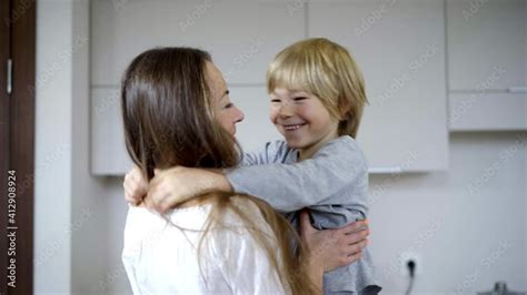Cheerful Mother And Son Rubbing Noses Hugging In Kitchen At Home Side View Portrait Of Happy