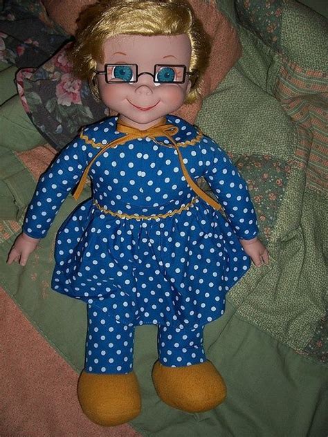 The Doll Is Wearing Glasses And A Blue Dress With White Polka Dots On