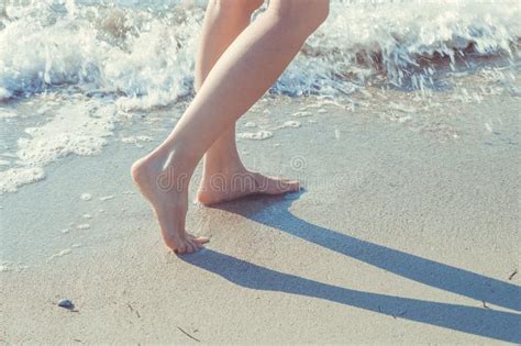 Close Up Of Woman Legs Walking Barefoot On Beach In Summer Holidays