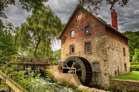 An Old Brick Building With A Water Wheel Next To It And Trees In The