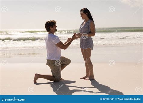 Kneeled Man Proposing A Woman To Marry Giving Red Box With Ring