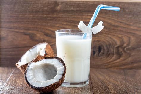 Coconut Halves With A Glass Of Coconut Milk On A Brown Wooden