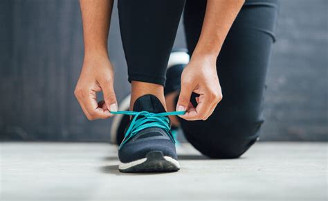 Female Runner Tying Her Shoes Preparing For A Run Chamberlins