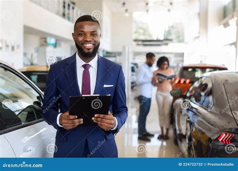 Handsome Black Car Salesman In Suit Posing At Workplace In Auto