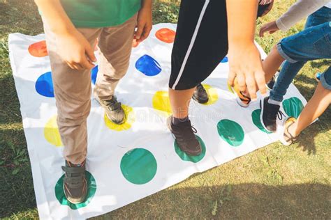 Children Playing A Twister On The Grass Legs On Red Stock Image