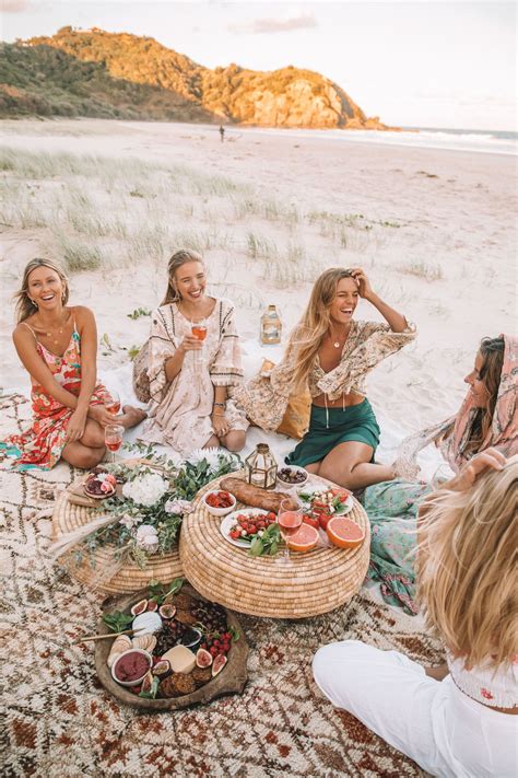 A Group Of Women Sitting On Top Of A Beach Next To Each Other Eating Food