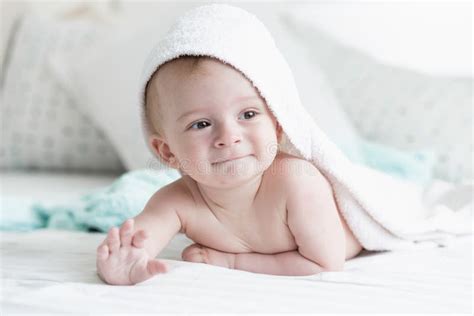 Cute 9 Months Old Baby Son Lying Under White Towel On Bed Stock Photo