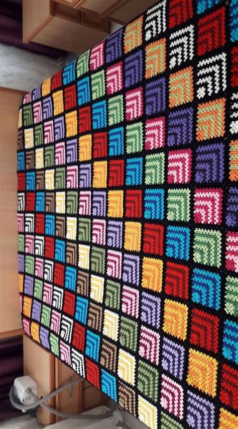 A Colorful Crocheted Blanket Hanging From The Side Of A Wall