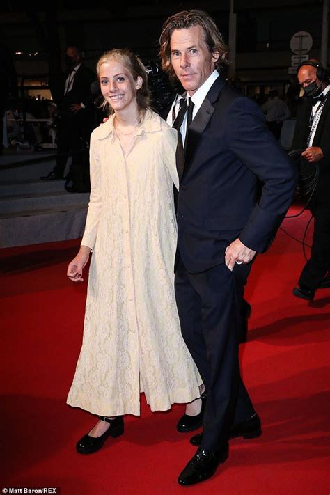 A Man And Woman Standing On A Red Carpet Next To Each Other At An Event