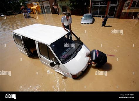 Two Men Trying To Restart Their Van Stuck In A Flooded Street In