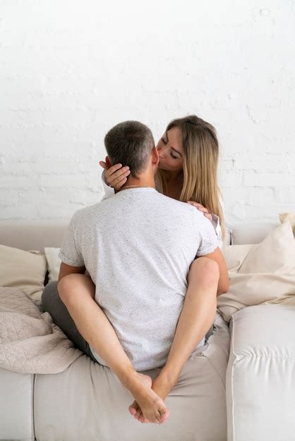 Tiro completo mujer besando a marido en el sofá Foto Gratis