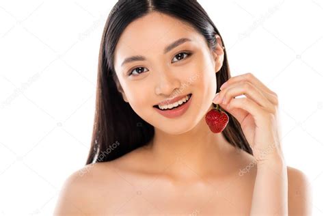 desnuda mujer asiática sosteniendo jugosa fresa mientras mira la cámara