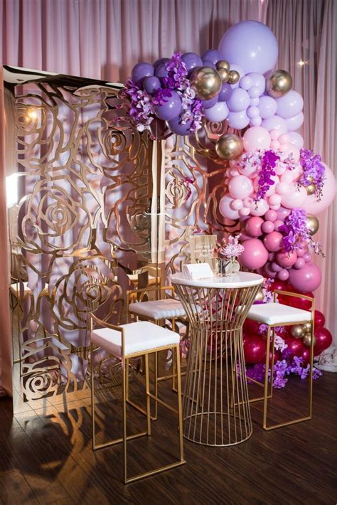 A Table And Chairs In Front Of A Wall With Balloons Hanging From Its Sides