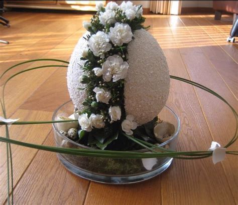 An Easter Egg Decorated With White Flowers In A Bowl On A Wooden Floor