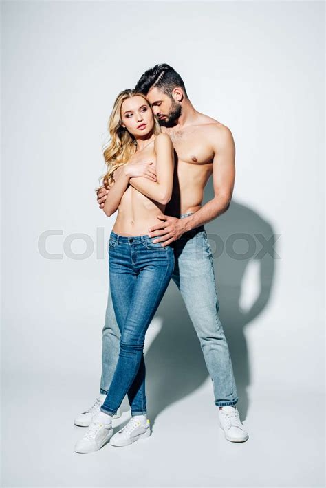 Handsome Man Touching Blonde Girl Covering Breasts While Standing On White Stock Image Colourbox