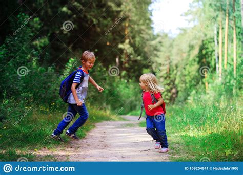 Happy Little Boy And Girl With Backpacks In Nature School Holidays