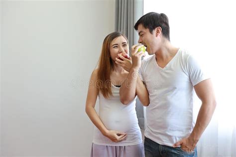 Medium Shot Of Young Caucasian Husband Embracing Young Asian Pregnant Belly Wife With Happiness