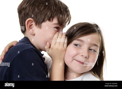 Two Children Whispering Into Each Others Ear Sharing A Secret Stock