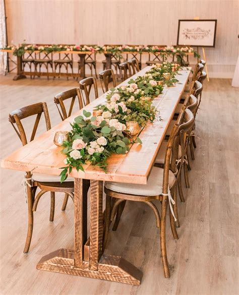 The Long Table Is Set With White Linens And Greenery