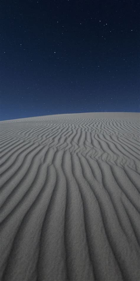 The Night Sky Is Lit Up By Stars Above An Expanse Of White Sand With