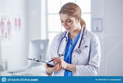 Young Woman Doctor Is Standing With Board With Clipboard Smilin Stock