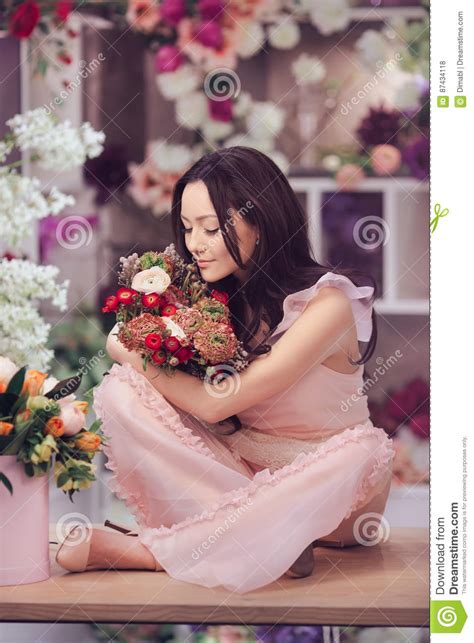 Beautiful Asian Woman Florist In Pink Dress With Bouquet Of Flowers In Hands In Flower Store