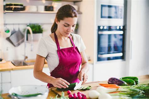 Closeup Of A Mature Woman Cutting Vegetables In Kitchen By Stocksy