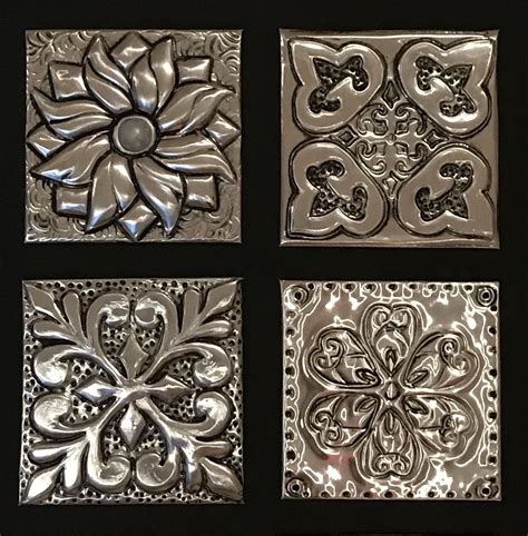 Four Square Metal Tiles With Designs On Them All In Different Shapes