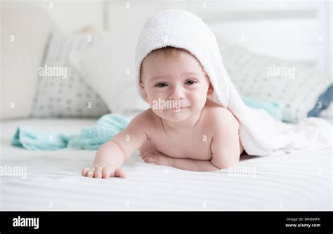 Portrait Of Smiling 9 Months Old Baby Boy Lying On Bed Under White