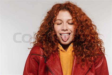 Portrait Of Funny Redhead Woman 20s Wearing Leather Jacket Smiling And Sticking Out Her Tongue