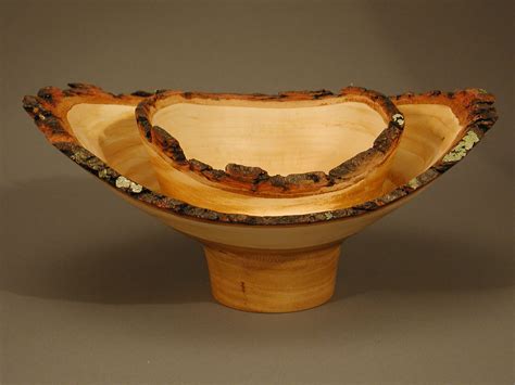 Two Wooden Bowls Sitting On Top Of Each Other In Front Of A Gray