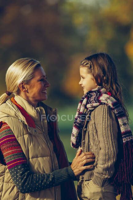Happy Mother And Daughter Looking At Each Other In Autumnal Park