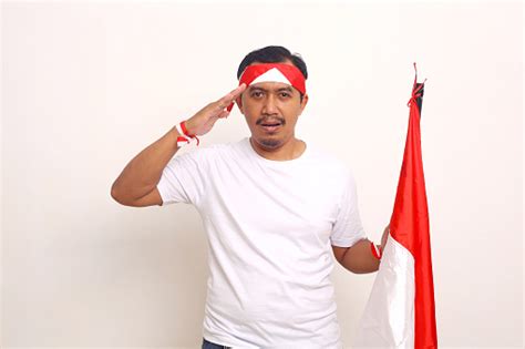 Pria Asia Berdiri Dengan Sikap Salut Sambil Memegang Bendera Indonesia