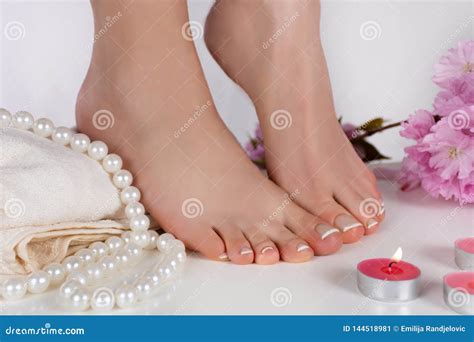 girl bare feet with french pedicure on white towel and decoration candle pearls and pink flower