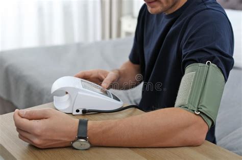 Man Checking Blood Pressure With Sphygmomanometer At Table Indoors