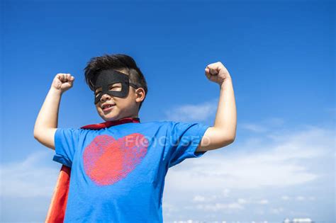 Superhero Kid Flexing His Muscles Against Blue Sky — Freedom Ocean