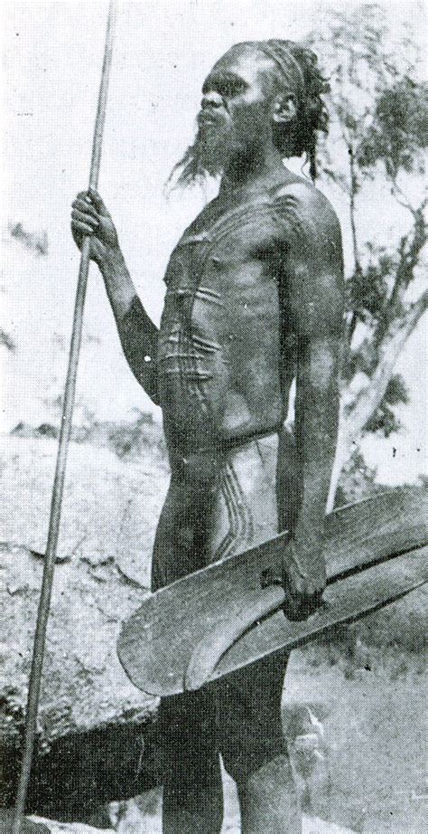 An Old Black And White Photo Of A Native American Man Holding A Surfboard In His Hand