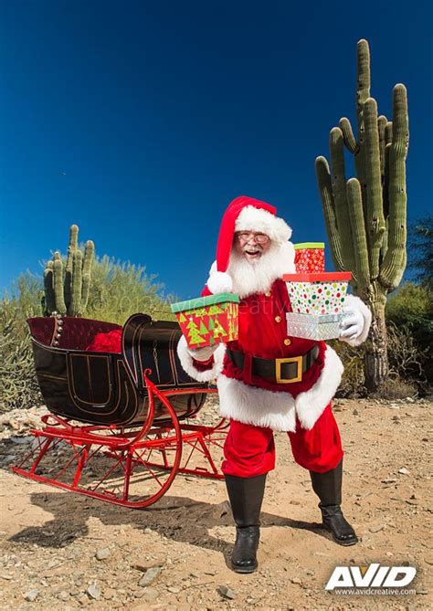 A Man Dressed As Santa Claus Carrying Presents In A Sleigh With Cacti
